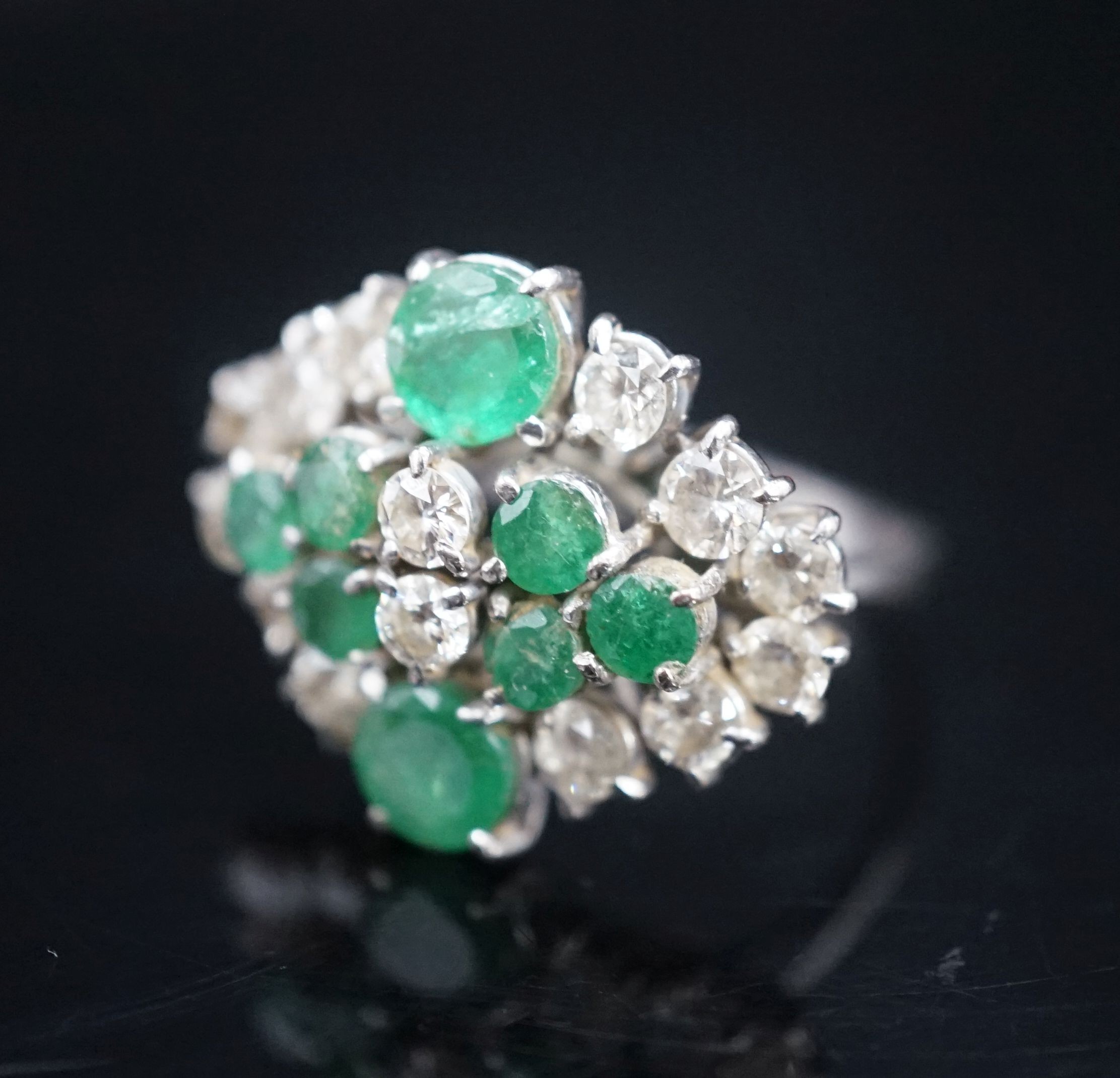 A 20th century 18ct white metal, emerald and diamond set cluster dress ring, size O/P, gross weight 7.3 grams.